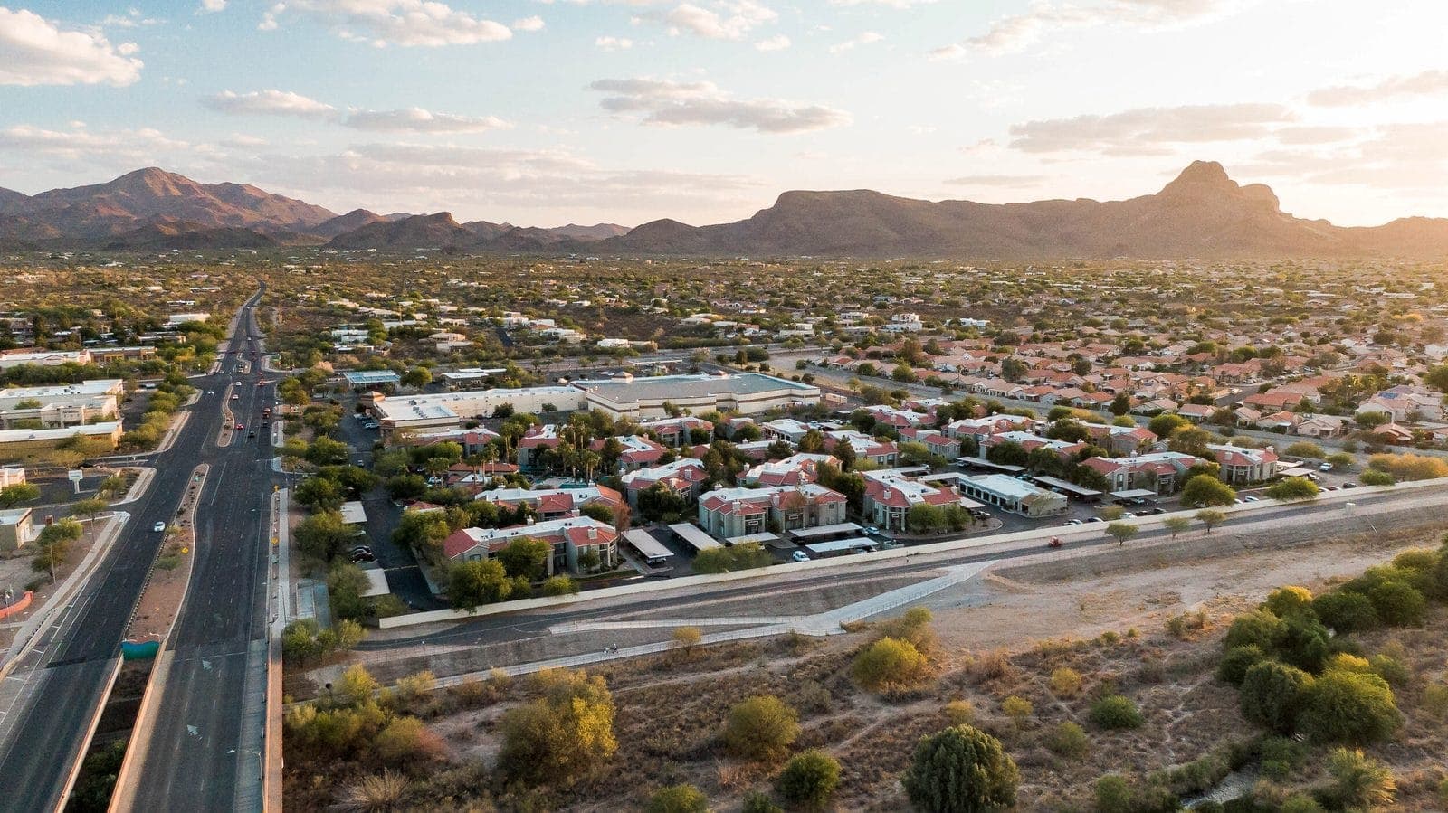 Aerial view of Marana apartments and businesses along a main road with the Tucson Mountains beyond
