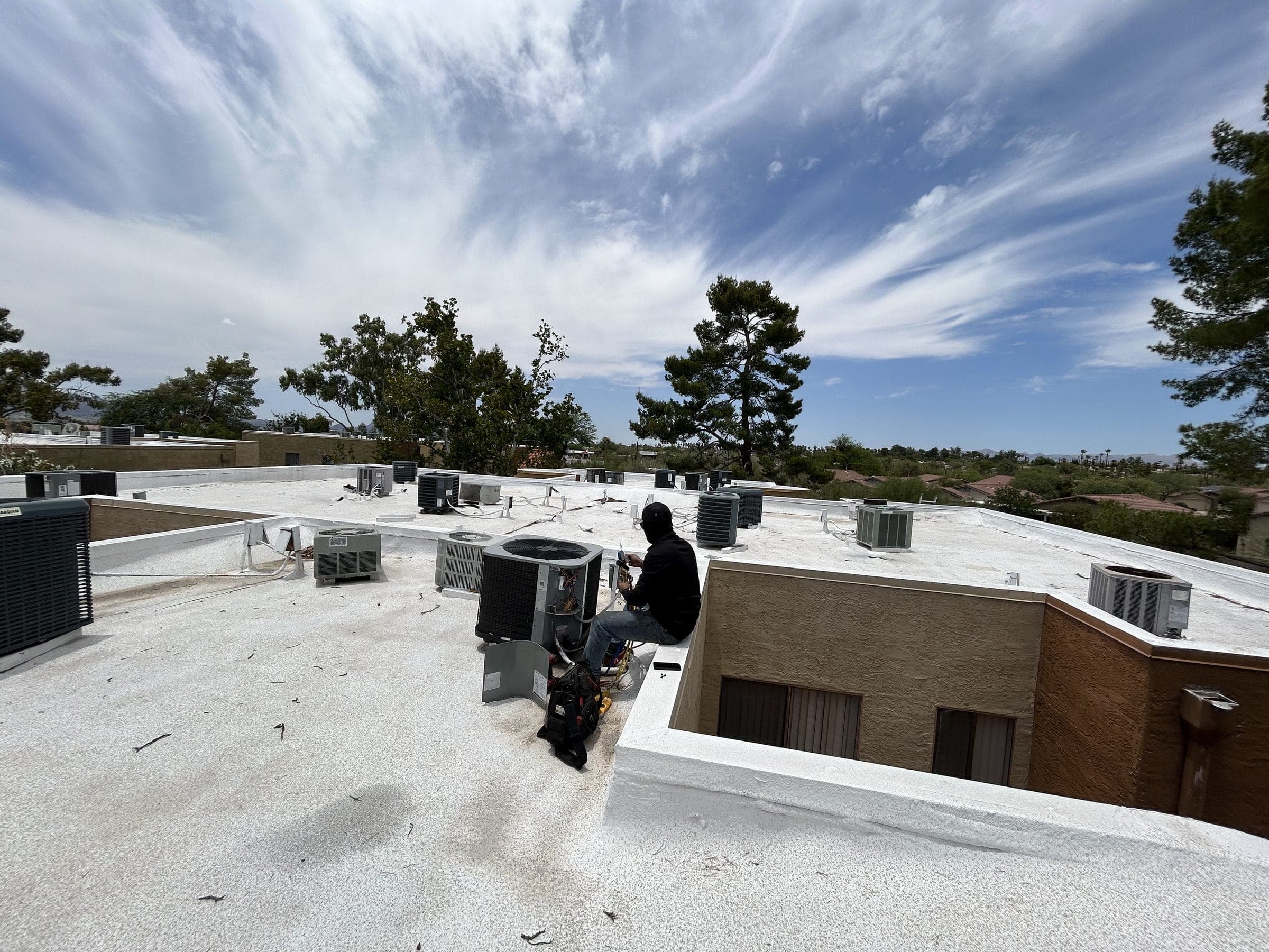 Victory Mechanical technician servicing a condenser on a rooftop lined with HVAC units