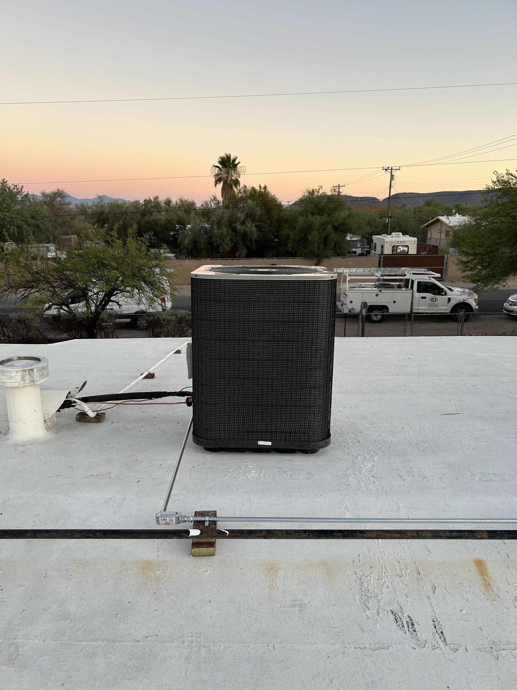 New rooftop condenser at sunset with a Victory Mechanical service truck parked below
